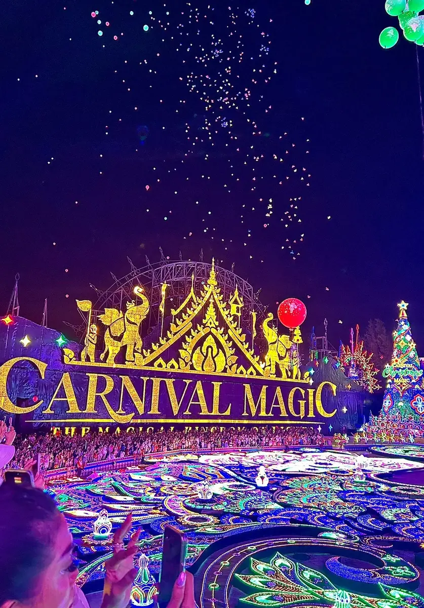 Glowing golden Carnival Magic sign and peacock light-floor at night