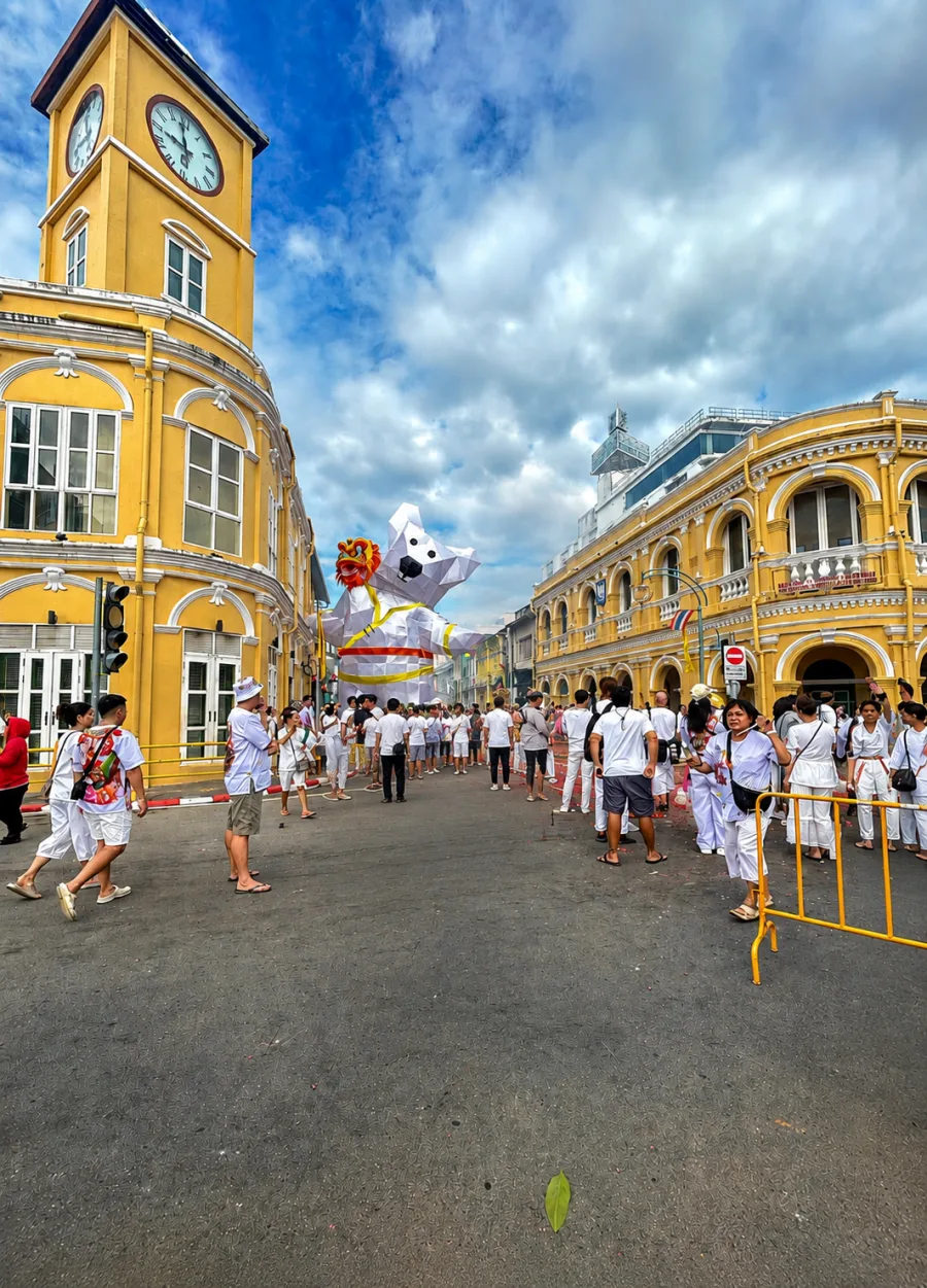ผู้คนชุดขาวและหุ่นโคมไฟหน้าหอนาฬิกาย่านเมืองเก่าภูเก็ต ในงานประเพณีถือศีลกินผัก